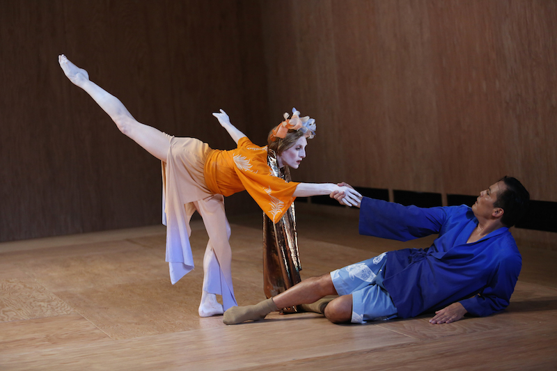 Jack Soto lays on the floor with one of his elbows prop him up while his other helps Wendy Whelan hold her balance in an arabesque penchee